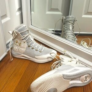 The high top gold and white hover Under Armour volleyball shoes, size 10.
